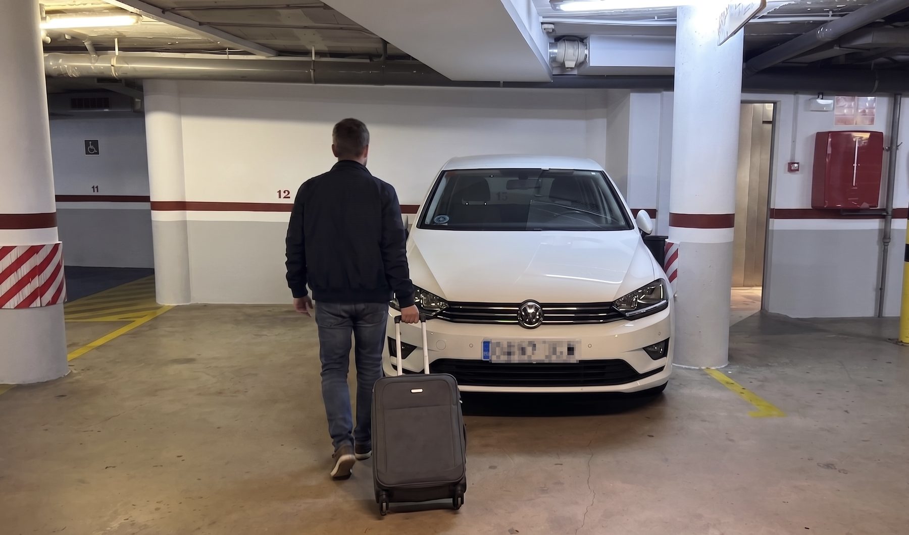 Hotel guest arriving with a suitcase at the private car park inside Hotel Ronda Lesseps, Barcelona
